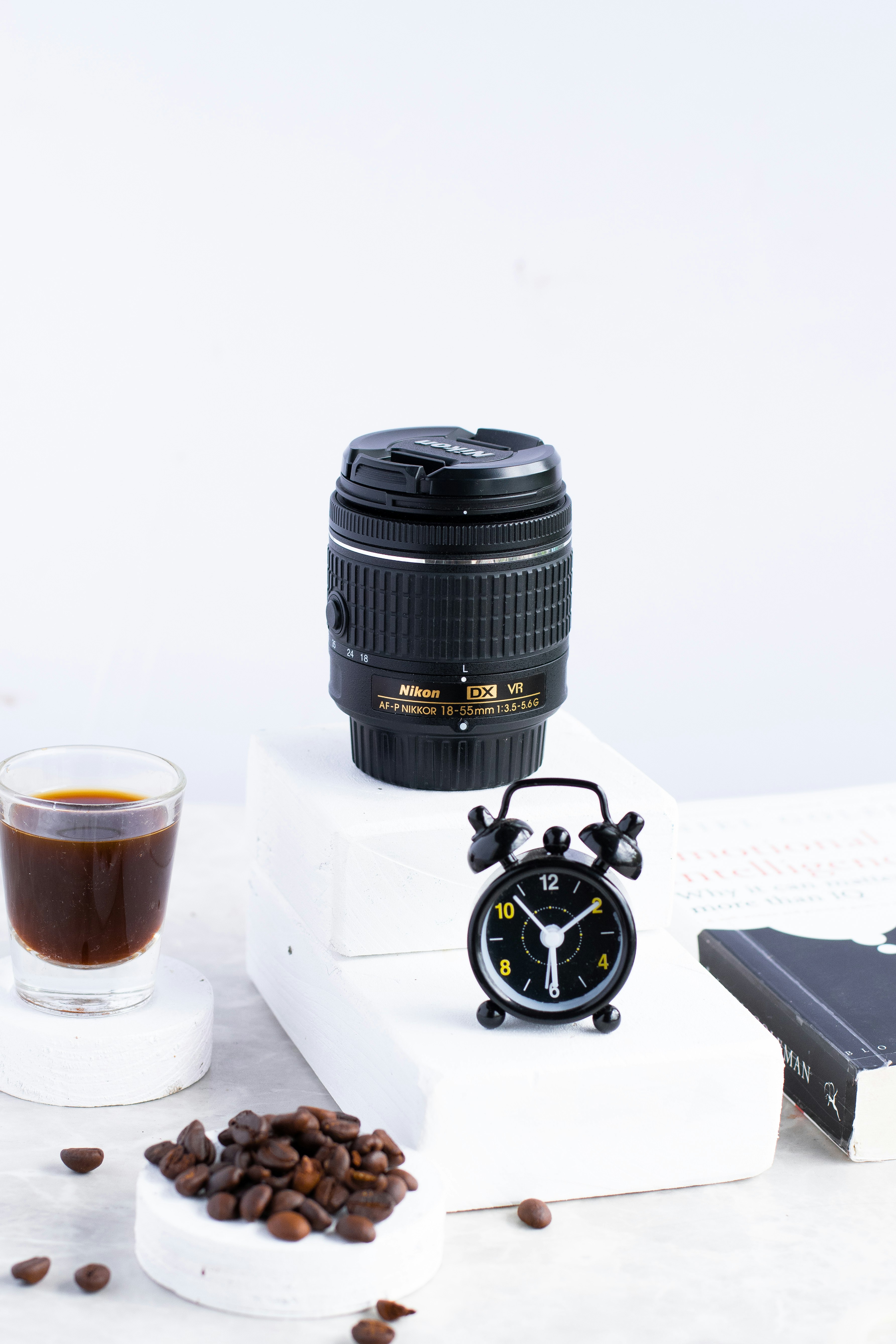 black camera lens beside white disposable cup on white table